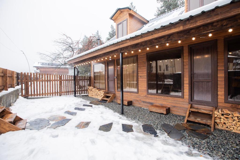 a house with snow on the ground next to a fence at Tatu's wooden hut in Mestia