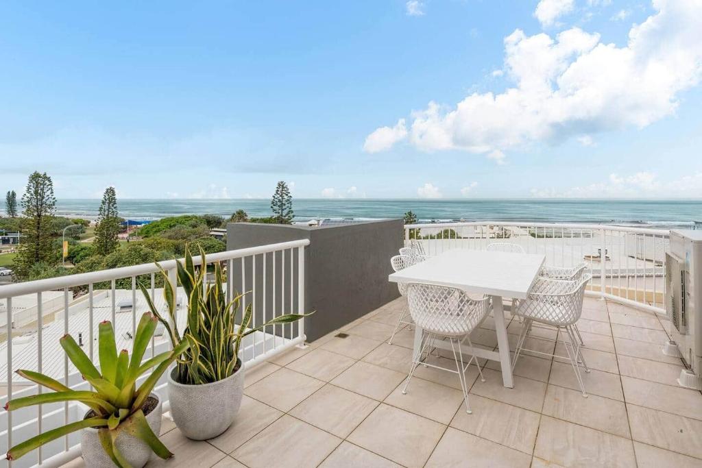 a balcony with a table and chairs and the ocean at Coolum Beach Retreat in Coolum Beach