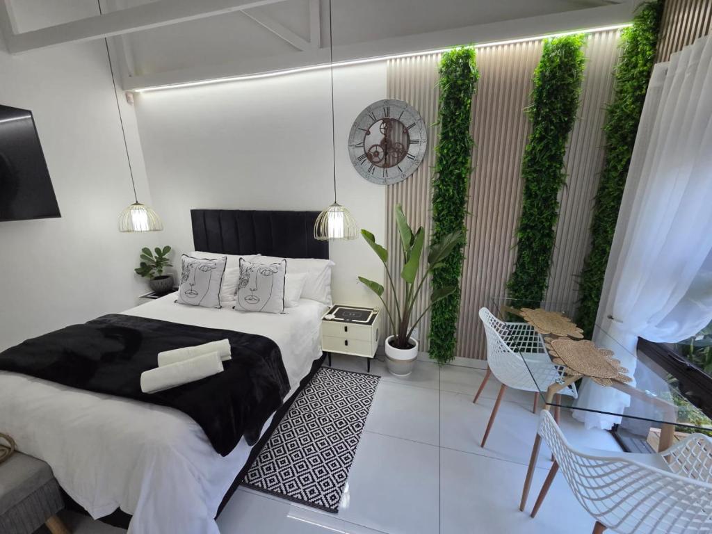 a bedroom with a bed and a balcony with plants at Indulge Deluxe Accommodation in Middelburg