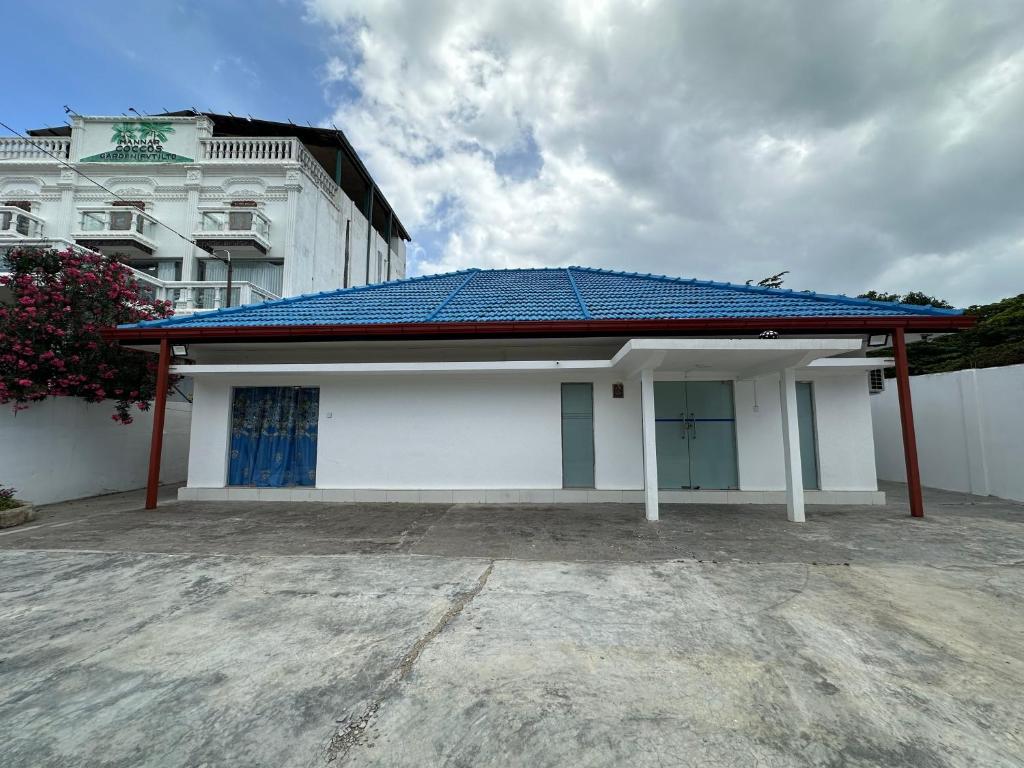a white building with a blue tin roof at Andrella Rest House in Mannar