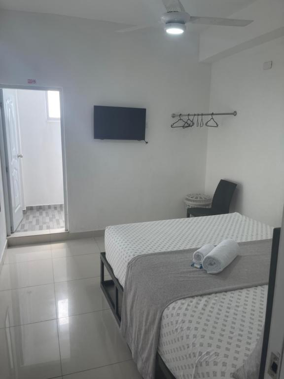 a white room with two beds and a television at Plata View Center Habitacion 2D in Monte Plata