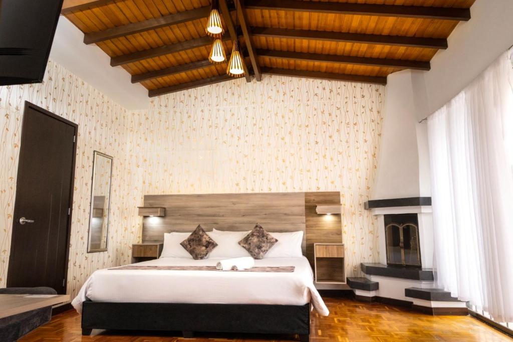 a bedroom with a large bed and a fireplace at Hotel Versalles Boutique in Pasto
