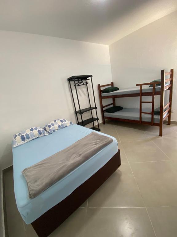 a bedroom with a bed and a chair in it at -TROPICAL SUÍTES- ao lado do SESC-BERTIOGA in Bertioga