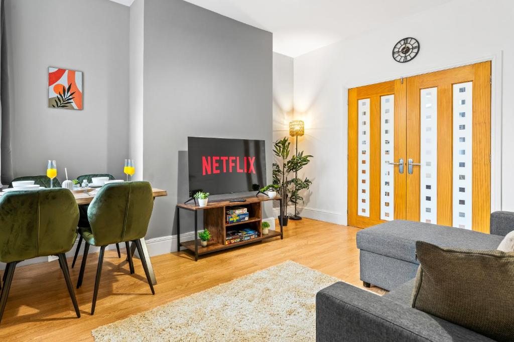 a living room with a table and a television at Comfortable 4 Bed Home - Free Parking & Brand New Bathroom in Denton