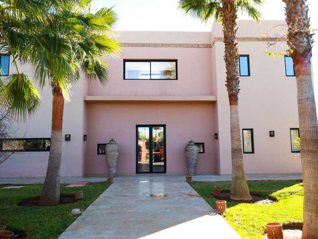 a pink building with palm trees in front of it at Villa des iris Domaines NAJMA in Marrakesh