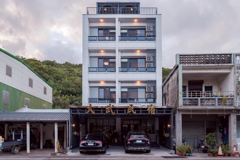 a white building with cars parked in front of it at Da Wu B&B 大武民宿-台東縣民宿2195號 in Shang-wu