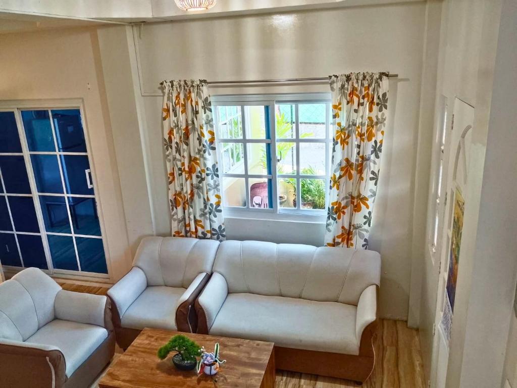 a living room with a white couch and two windows at Rustic Retreat Three Bedroom House in Pagdalagan