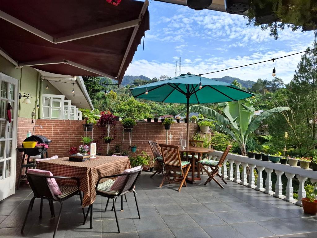 a patio with tables and chairs and an umbrella at ParabonHaus Kopitiam - Bed & Breakfast in Gegarbensang