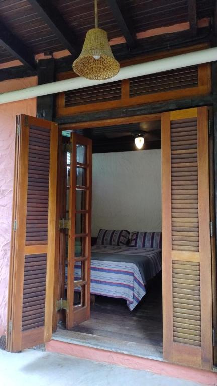 a bedroom with a bed in a room with open doors at Suite casa cachoeira in Paraty