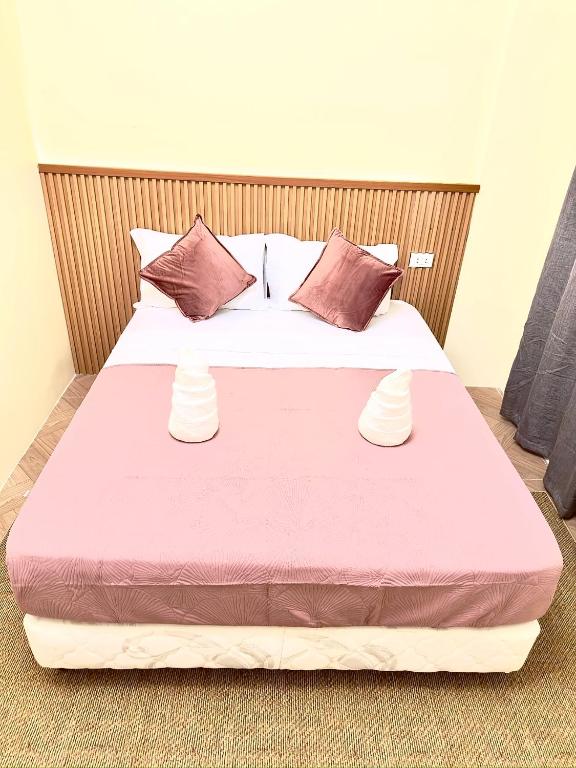 a bedroom with a large bed with pink sheets and pillows at RV3 Prime Suites & Apartelle in Angeles
