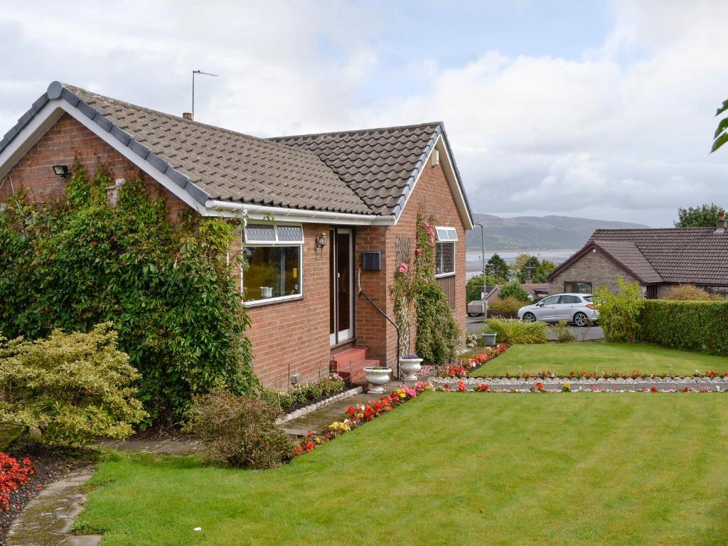 a brick house with a yard with flowers at Glencairn Rd in Langbank