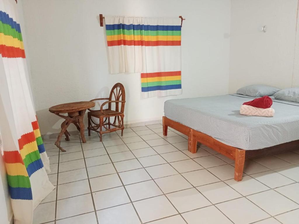 a room with a bed and a table with a rainbow curtain at Casa luci in Zipolite