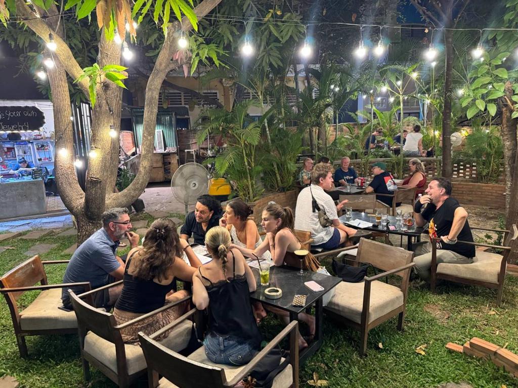a group of people sitting at tables in a restaurant at Pomme Brewhouse Hostel in Siem Reap