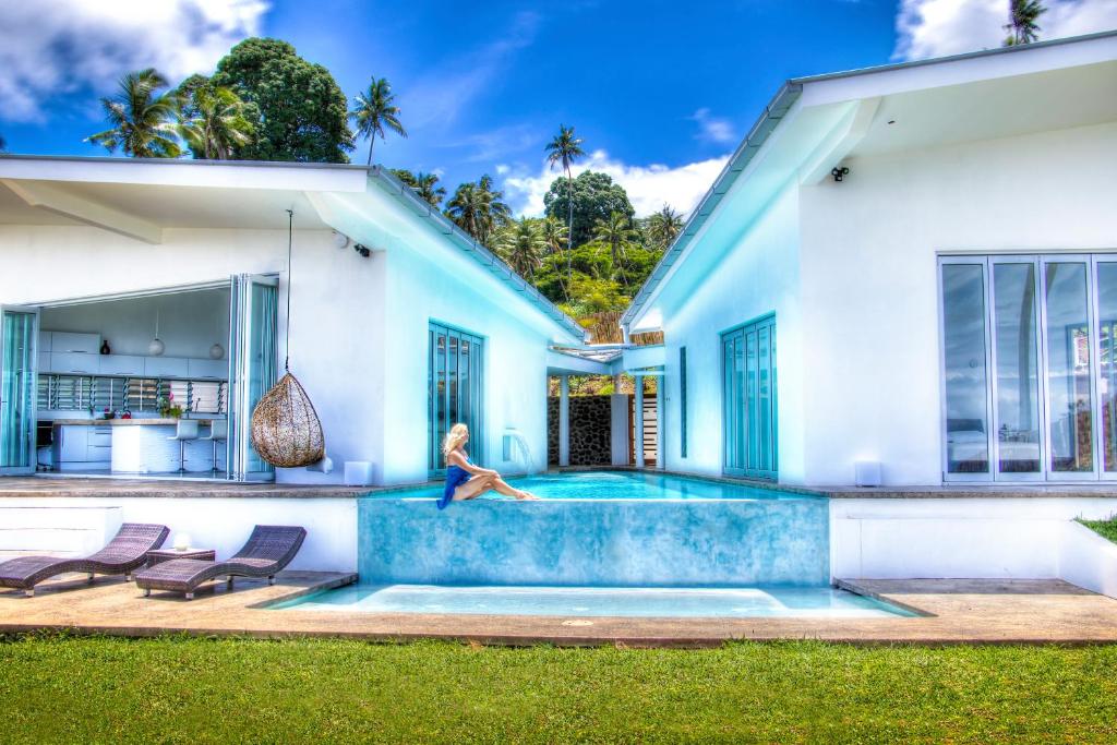 a woman sitting on the edge of a pool in a house at Vacala Bay Resort in Matei