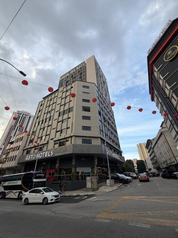 a tall building on a street with cars parked in front at Asto Hotel Kuala Lumpur in Kuala Lumpur