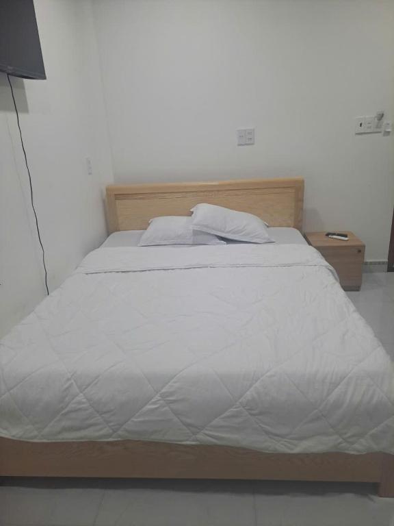 a large white bed with a wooden head board at Hotel Hải Âu in Kỳ Trân (1)