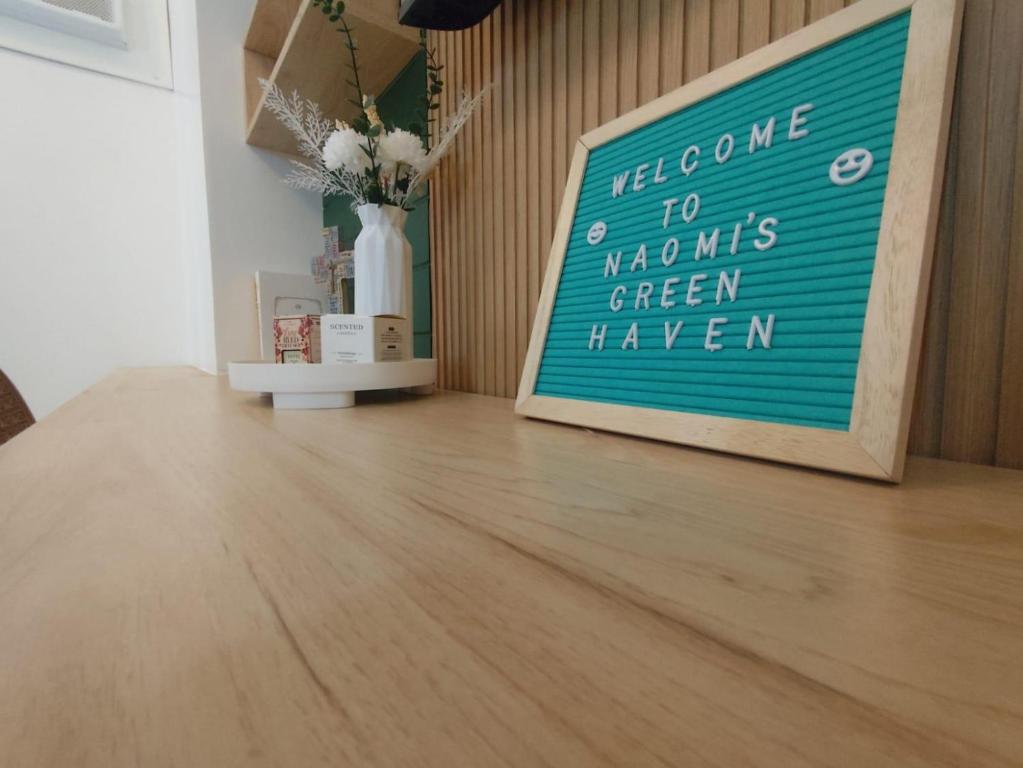 a sign sitting on a wooden floor in a room at Naomi's Green Haven in Dasmariñas