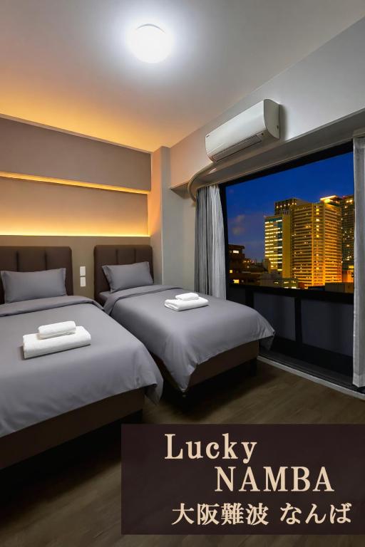 a room with two beds and a window with a city skyline at Lucky NAMBA 大阪難波 なんば in Osaka