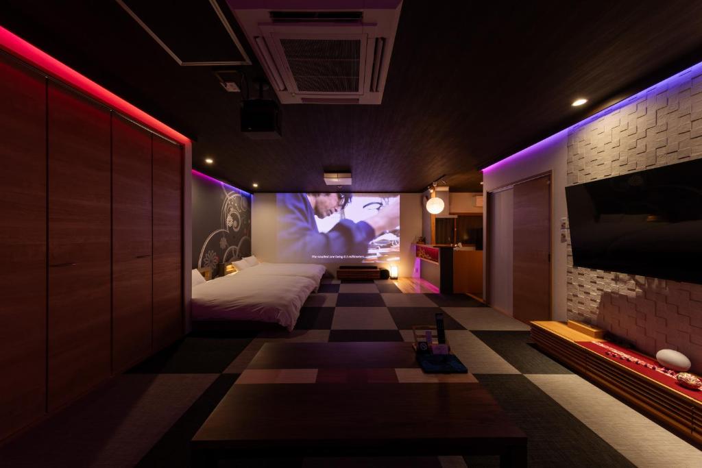 a bedroom with a bed and a tv on a wall at Tsuzumi Suite - Private Cinema & Immersive Stay in Kanazawa in Housai