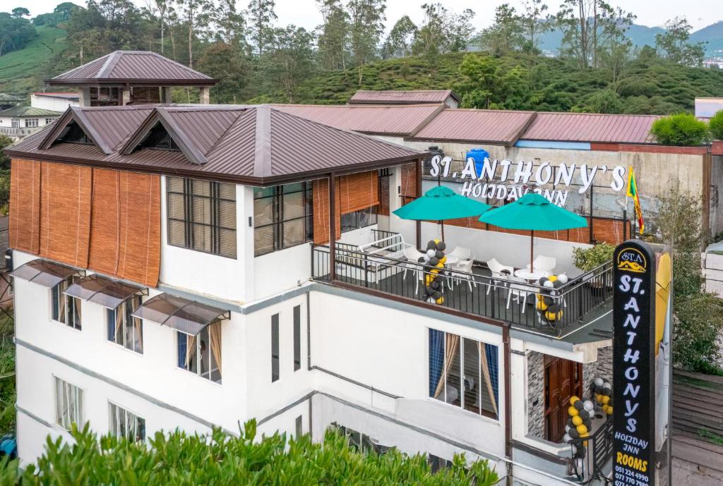 a hotel building with a balcony with umbrellas at St Anthonys Holiday Inn in Kotagala