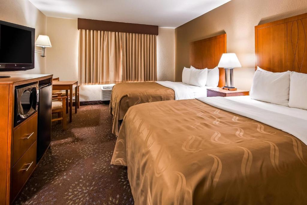 a hotel room with two beds and a flat screen tv at Quality Inn Tomah in Tomah
