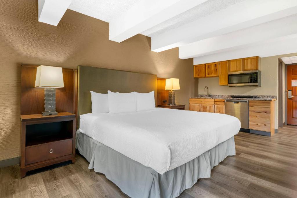 a bedroom with a large bed and a kitchen at Fairway Inn and Suites, an Ascend Collection Hotel in Mishicot