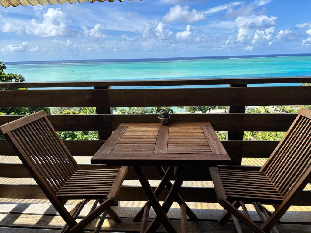 a table and chairs on a balcony with the ocean at Matira Hills Apartment in Bora Bora