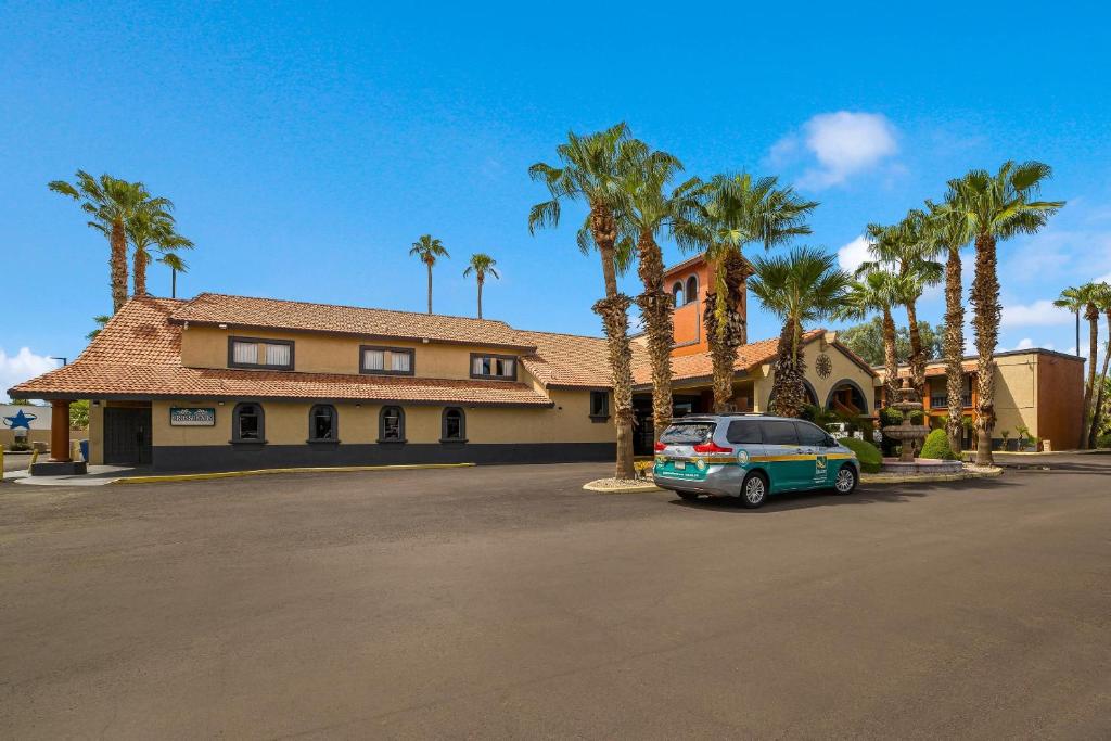 a car parked in front of a house with palm trees at Quality Inn & Suites Goodyear - Phoenix West in Goodyear