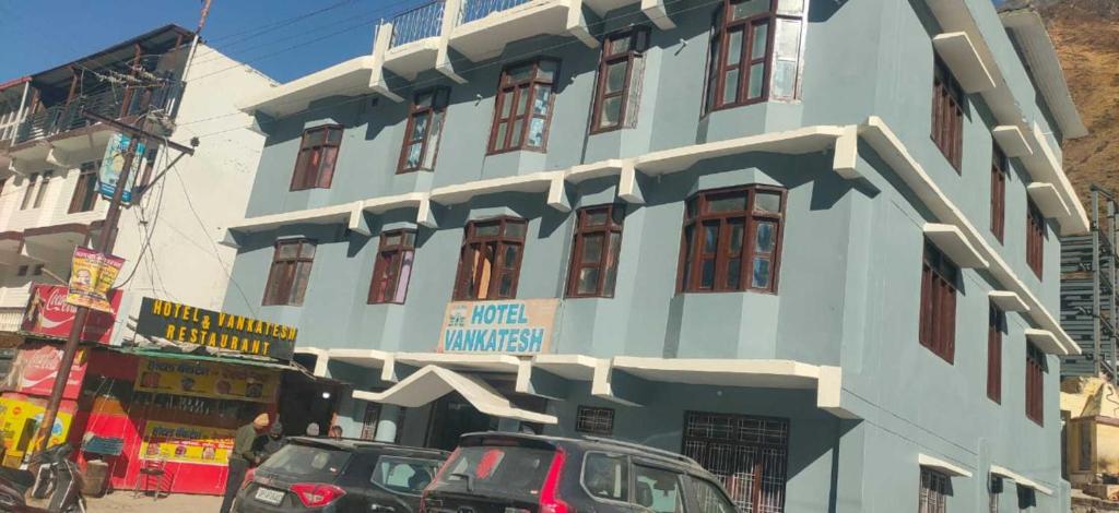 a blue building with cars parked in front of it at Hotel Venkatesh in Badrinath
