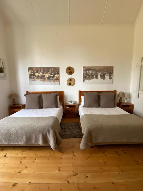 two beds in a room with wooden floors at Mon Desir Estate - BR4 in Pietermaritzburg