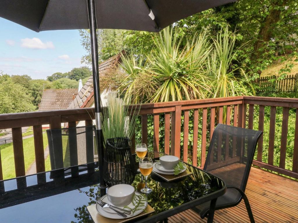a table and chair on a deck with an umbrella at Lavender Lodge in Callington