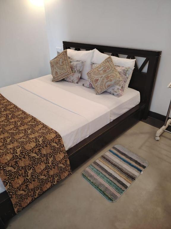 a large bed with pillows and a rug in a room at Charlotte Inn in Kandy
