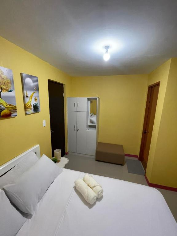a bedroom with a white bed and yellow walls at Casa Solana at Malaybalay VCDU Phase 3 B4 L22 in Malaybalay