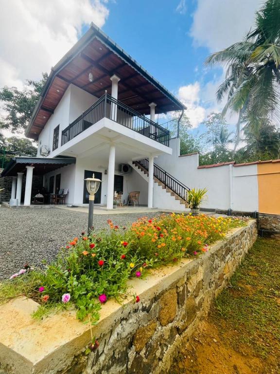 a white building with a balcony and some flowers at The villa Evans in Pitiduwa