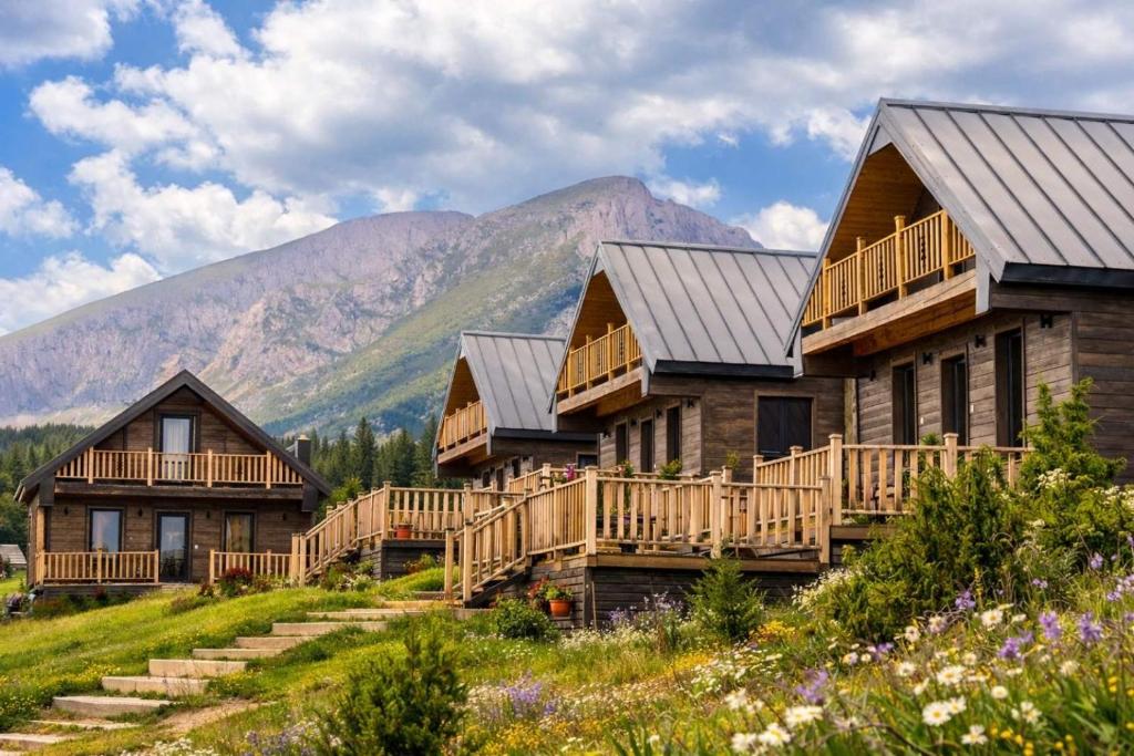 a row of log homes on a hill with mountains at Adria Nord Chalets in Žabljak