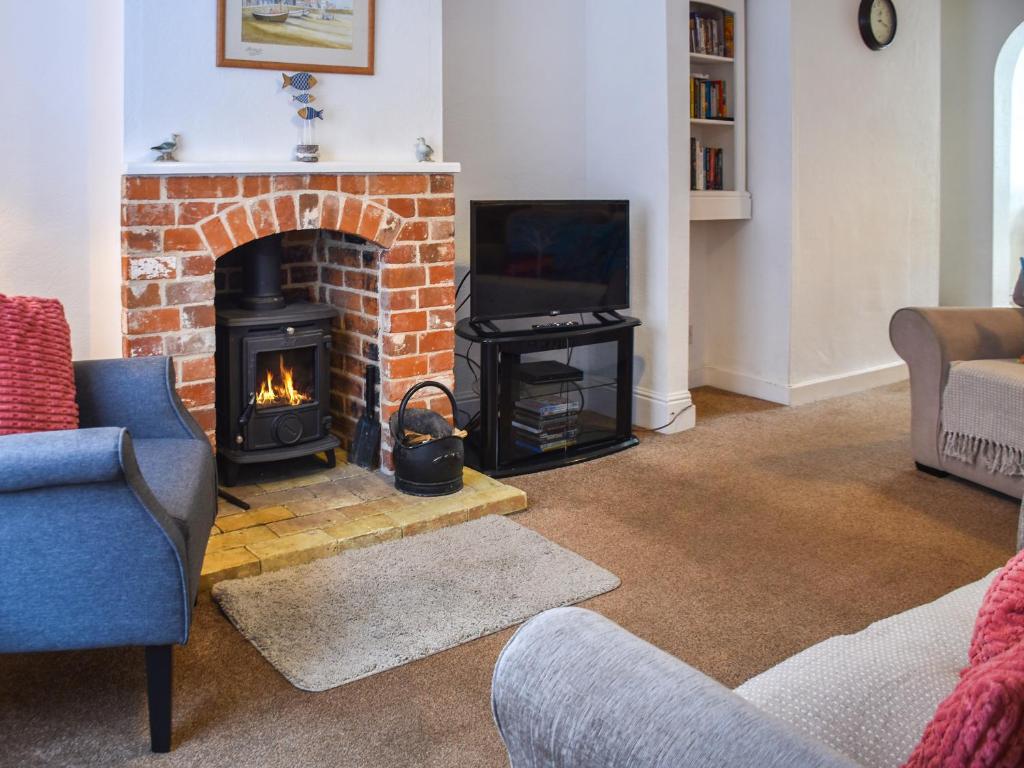 a living room with a brick fireplace with a stove at Maydrift in Mundesley