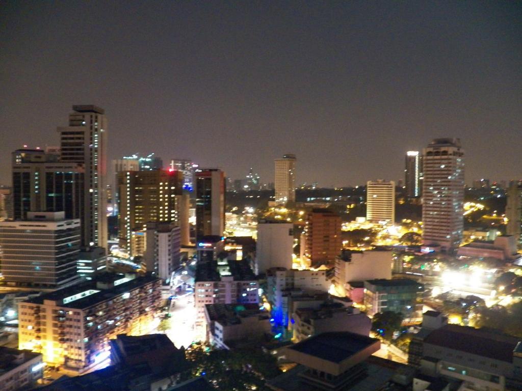 un perfil urbano por la noche con edificios iluminados en Maytower Apartment en Kuala Lumpur
