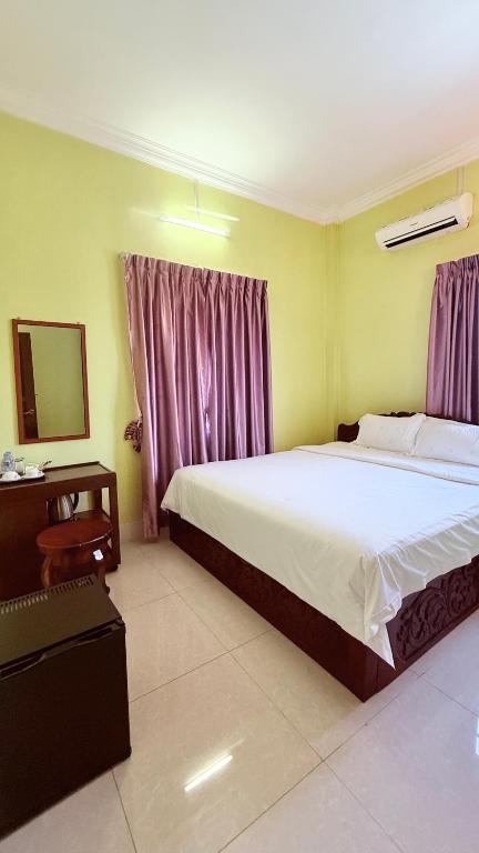 a bedroom with a large bed and a mirror at Angkor Sandra Villa in Siem Reap