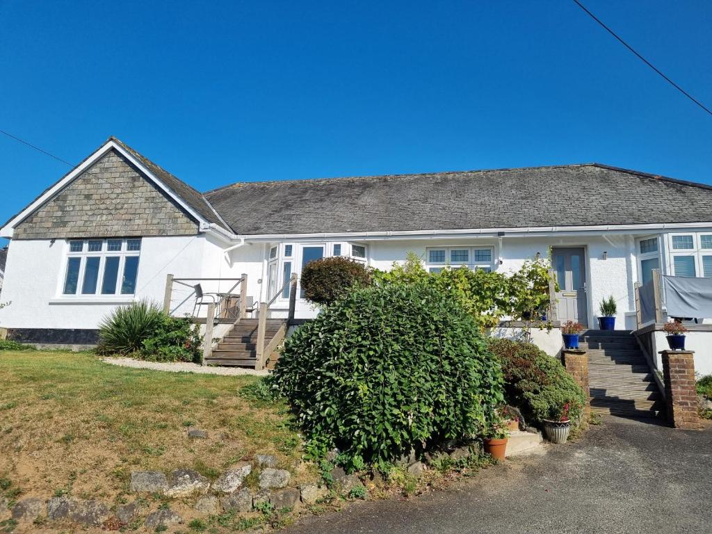 a white house with a porch and stairs at Halwyn View in St Austell