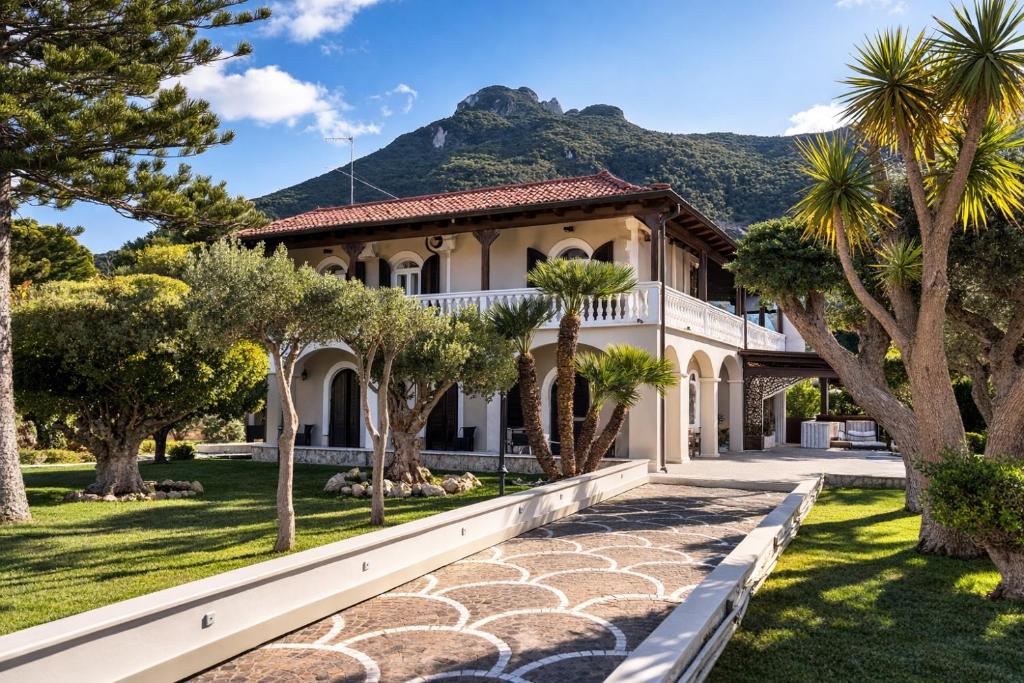 a house with palm trees and a mountain in the background at Villa Antonietta Ischia in Forio d'Ischia