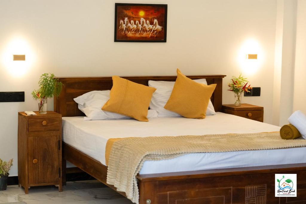 a bedroom with a wooden bed with yellow pillows at Sinharaja Cascade Villa in Deniyaya