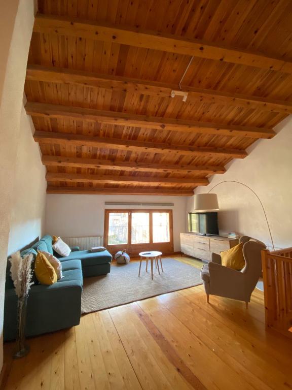 a living room with a blue couch and a wooden ceiling at Ca La Pausa in Alpens
