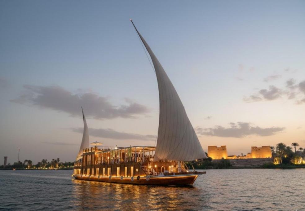 a sail boat with a building on the water at Amber Dahabiya in Luxor