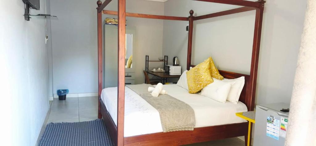 a bedroom with a canopy bed with white sheets and yellow pillows at Sthuli House in Empangeni