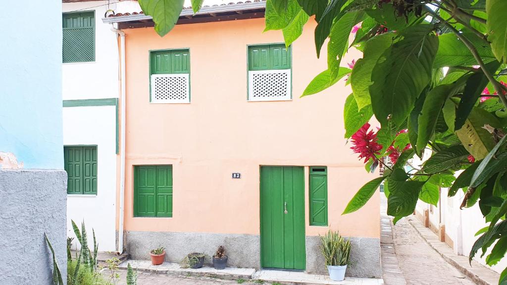 a green door on a pink building with green windows at Casa de Nara in Lençóis