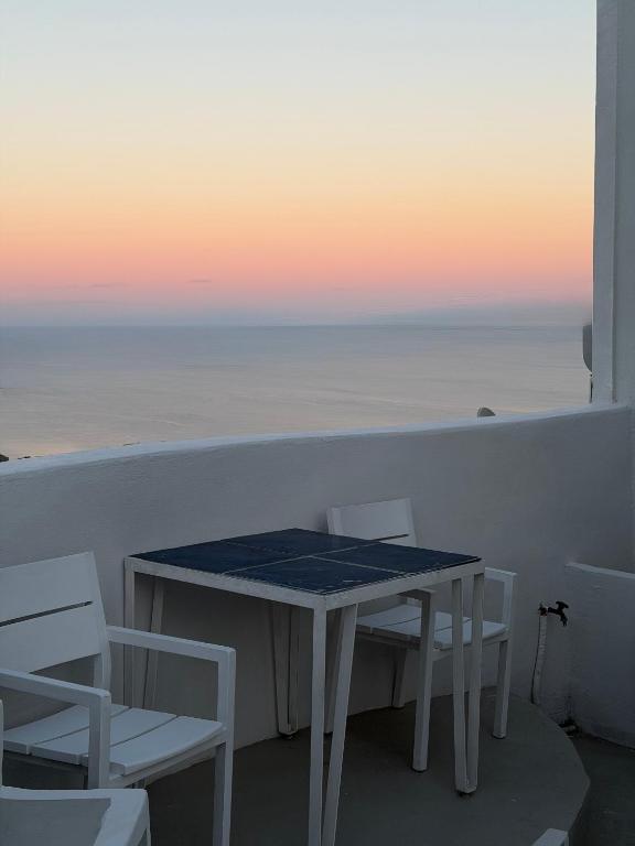 a table and chairs on a balcony with the ocean at White Swallow Suite Santorini in Vourvoúlos