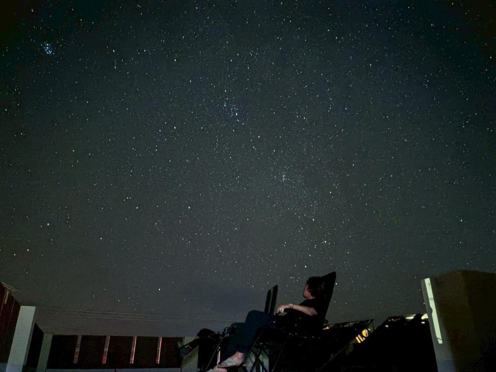 a person sitting in a chair looking up at the stars at Adventure Hostel う島や in Iriomote