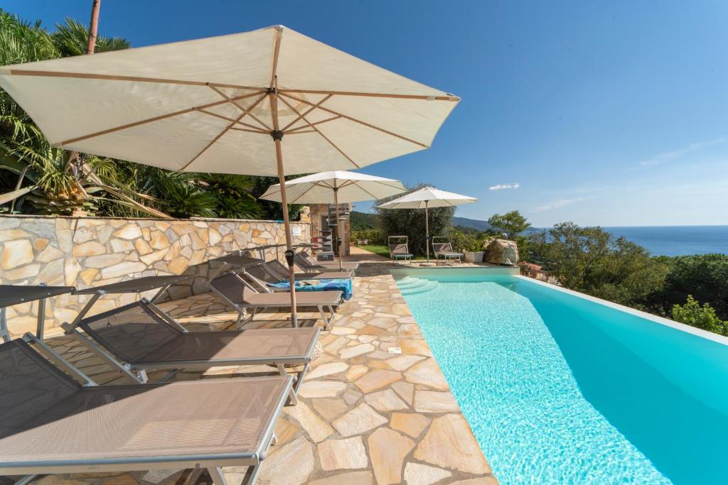 a swimming pool with umbrellas and chairs and a swimming poolvisor at Villa di Sogno in Palazzo