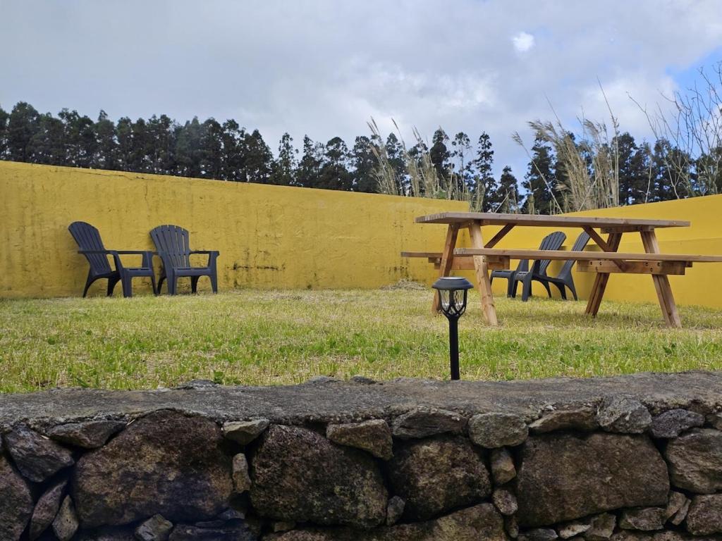 a park with chairs and a picnic table and a fence at The Yellow Cottage in Lomba de São Pedro