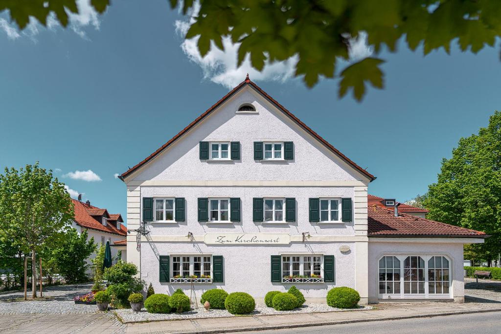 a large white house with green shuttered windows at Zum Kirchenwirt in Anzing